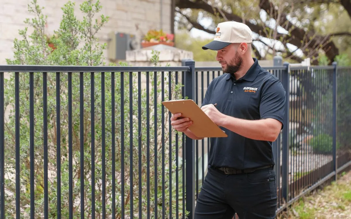 Professional fence installation by EleFence fence installers inspecting ornamental iron fence at residential property in Austin TX